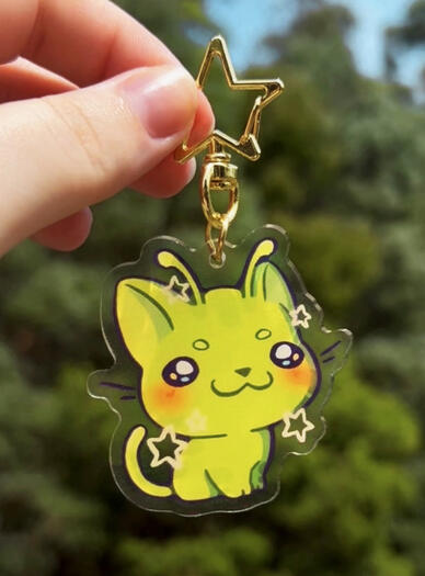 Image shows a hand holding an alien cat keychain