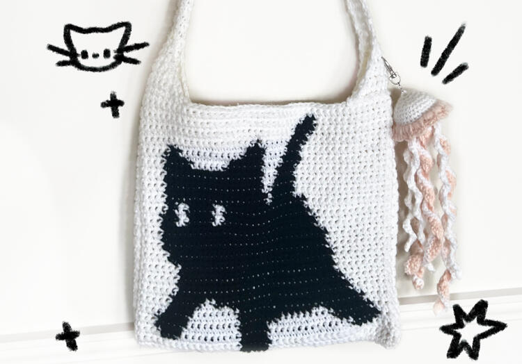 Image shows a white crochet bag with a black cat on it