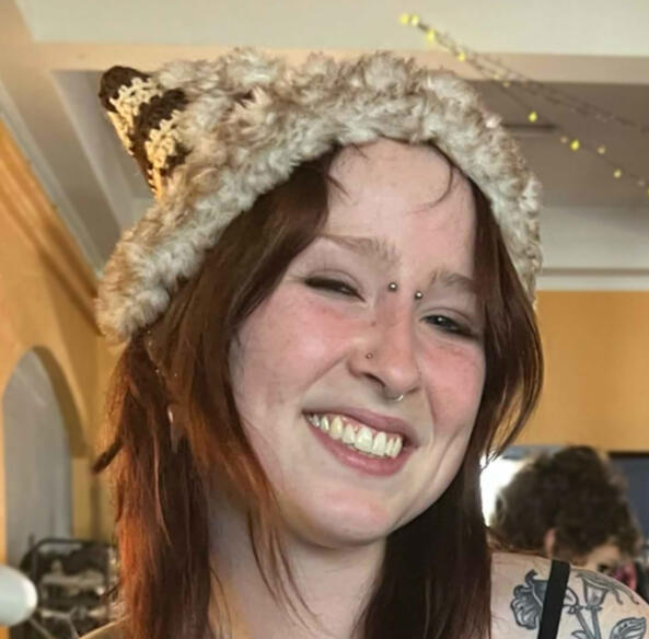 Image shows a person wearing a brown crochet cat hat with a fur trim